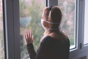 Woman in mask staring out of window